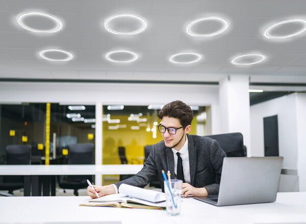 Round LED panel ceiling lights illuminating a modern office workspace